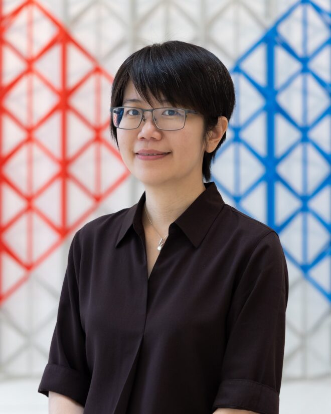 Dr I-Chen Hsieh, Academic Skills Tutor and Coordinator, smiling in front of a red, white and blue lattice screen.