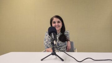 Dr Gurdofarid Miskinzoda smiling at a table behind a studio microphone during a Voices of IIS recording.