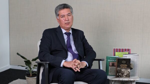 Safe: A speaker talks to camera in a studio, seated beside books including Russian Scholars on Ismailism.