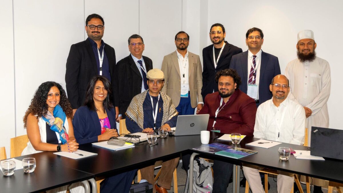 Eleven Gulf Research Centre Cambridge workshop participants around a meeting table, five seated and six standing.