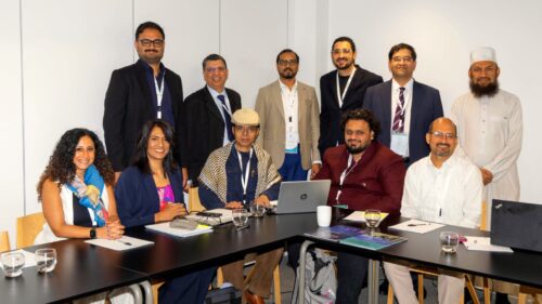 Eleven Gulf Research Centre Cambridge workshop participants around a meeting table, five seated and six standing.